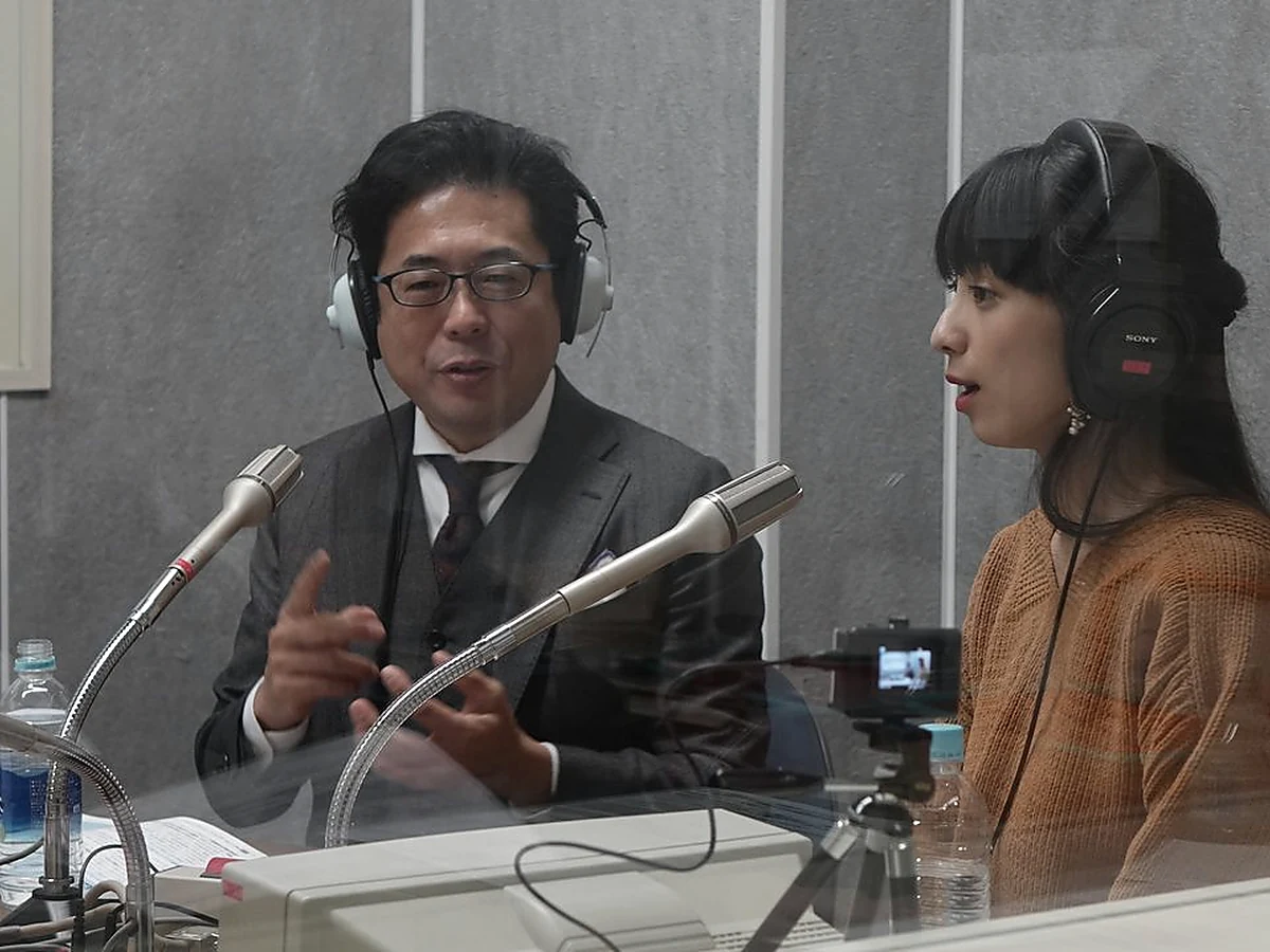 A thoughtful Japanese business owner beside a tidy recording desk, no visible text